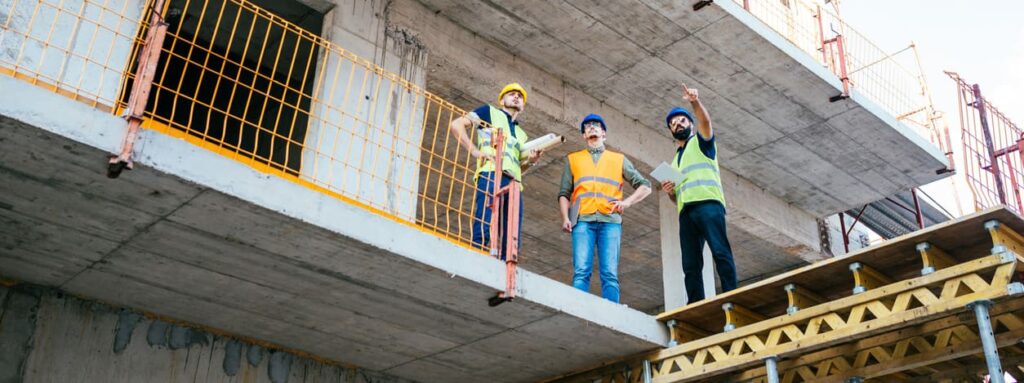 drie personen op een bouwplaats in gesprek